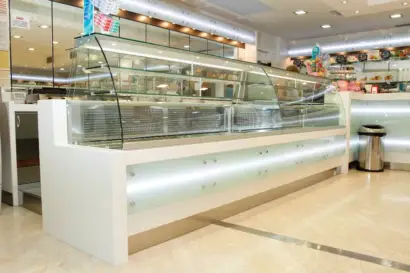 Vetrina refrigerata con vetro curvo su bancone in Corian e vetro bianco latte